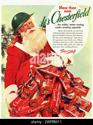 „IT’s More than ever Chesterfield Cooler-Smoking Cigarettes“ Eine Vintage-Werbung aus dem Zweiten Weltkrieg aus den Vereinigten Staaten für Chesterfield-Zigaretten. Das im klassischen Grafikstil gerenderte Bild zeigt eine Figur in einem Weihnachtsmann-Outfit mit einem großen Stapel Chesterfield-Zigarettenpackungen. Der Hintergrund ist hellgrün, mit einem Weihnachtsbaum auf der linken Seite verziert, der der Werbung einen festlichen Touch verleiht.- amerikanische Werbung (USA), Ära des Zweiten Weltkriegs Stockfoto