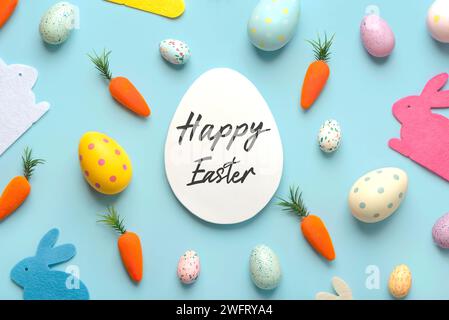 Frohe Ostern. Komposition mit bunten ostereiern, osterhasen und Karotten mit einem weißen Ei in der Mitte mit Text Happy Easter over Blue Backgrou Stockfoto