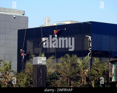 Kairo, Ägypten, 23. Januar 2024: Wartung und Reinigung des Außenbereichs eines Gebäudes, Glasreinigung durch Arbeiter an Drähten, um Reinigungsservice durch zu erbringen Stockfoto