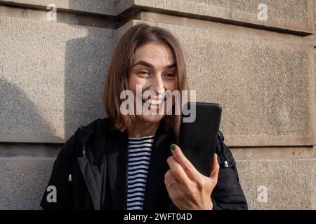 Lächelnde Frau, die ihr Smartphone ansieht Stockfoto