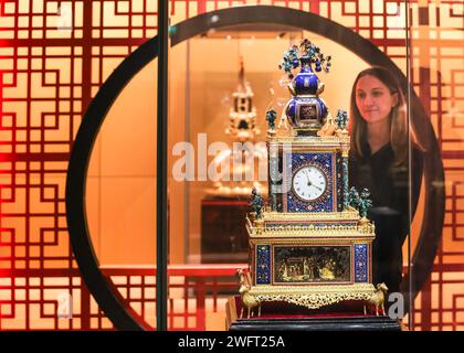 London, Großbritannien. Februar 2024. Museumsmitarbeiter posieren mit einem wunderschönen Zimingzhong (einzelne Uhren sind nicht betitelt, sondern tragen Beschreibungen). Zimingzhong: Uhrwerk Schätze aus Chinas Verbotener Stadt zeigt 23 kunstvoll verzierte und seltene chinesische Uhrwerk-Automaten, bekannt als zimingzhong, die für ihr kompliziertes Design geschätzt und von chinesischen Kaisern in den 1700er Jahren gesammelt wurden Quelle: Imageplotter/Alamy Live News Stockfoto