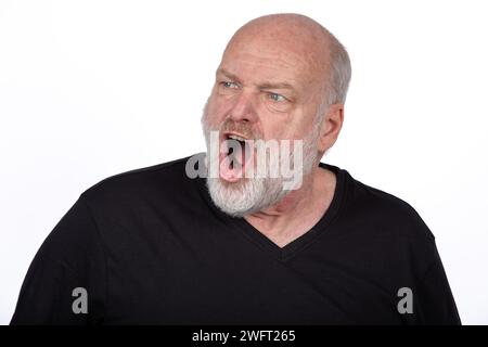 Intensiver mittelalter bärtiger Mann, der mit Wut in schwarzem T-Shirt brüllt, ausdrucksstarke Gesichtsgefühle auf weißem Hintergrund - starkes emotionales Porträt Stockfoto