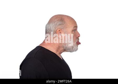 Profil Porträt, Bärtiger Mann mittleren Alters in schwarzem T-Shirt, das die Zunge ausstreckt - verspielter Humor auf weißem Hintergrund Stockfoto