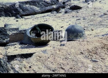 Erster Golfkrieg: 4. März 1991 Helme irakischer Soldaten in der Wüste, neben der Route 801, der Straße nach um Qasr, nördlich von Kuwait City. Stockfoto