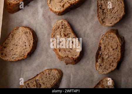 Handwerkliche Mehrkornbrotscheiben auf Backpapier. Stockfoto