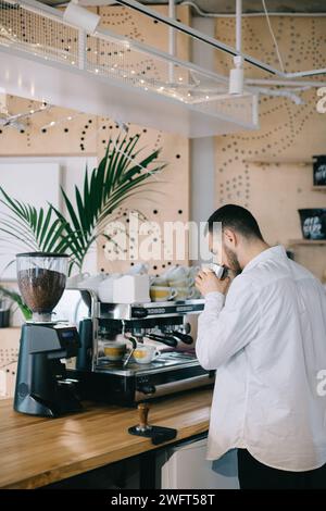 Ein Barista in der Nähe einer Espressomaschine bereitet leckeren Kaffee zu. Ein junger Mann bereitet Kaffee in einem Café zu. Stockfoto
