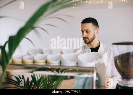 Ein Barista in der Nähe einer Espressomaschine bereitet leckeren Kaffee zu. Ein junger Mann bereitet Kaffee in einem Café zu. Stockfoto