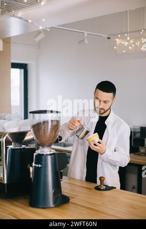 Ein Barista in der Nähe einer Espressomaschine bereitet leckeren Kaffee zu. Ein junger Mann bereitet Kaffee in einem Café zu. Stockfoto