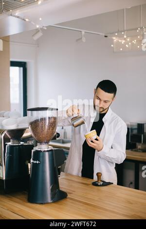 Ein Barista in der Nähe einer Espressomaschine bereitet leckeren Kaffee zu. Ein junger Mann bereitet Kaffee in einem Café zu. Stockfoto