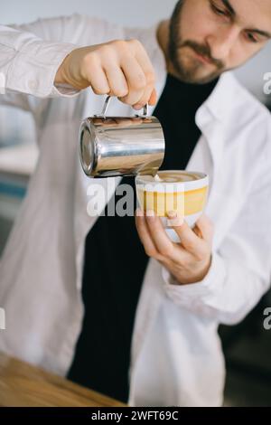 Ein Barista in der Nähe einer Espressomaschine bereitet leckeren Kaffee zu. Ein junger Mann bereitet Kaffee in einem Café zu. Stockfoto