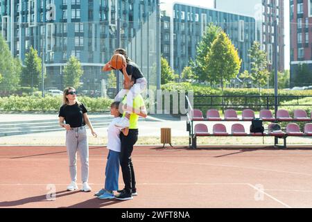 Die Familie spielt Basketball auf dem Platz Stockfoto