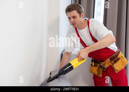 Man-Reinigungspersonal Hand in schützenden Gummihandschuh Reinigung Sofa mit professionell Extraktionsverfahren. Anfang Frühling regelmäßige Reinigung Stockfoto