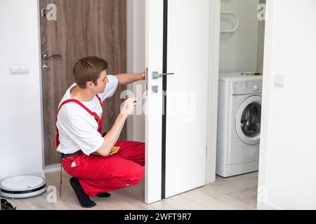 Bohren und Einbau von Innentüren, macht der Handwerker ein Loch in den Türrahmen mit einem Handbohrer, Türen und Montage. Stockfoto