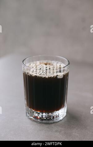 Frisch gebrühter Tropfkaffee in einem Glasbecher. Eine Tasse Kaffee auf grauem Hintergrund. Stockfoto
