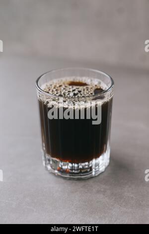 Frisch gebrühter Tropfkaffee in einem Glasbecher. Eine Tasse Kaffee auf grauem Hintergrund. Stockfoto