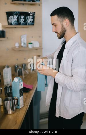 Ein Barista gießt Milch aus einem Karton. Der Prozess der Zubereitung von Kaffee oder Matcha. Stockfoto