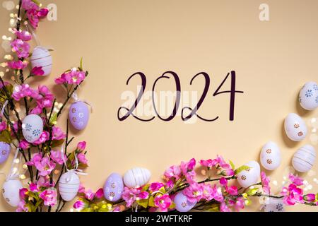 Englischer Text 2024 Auf Beigefarbenem Hintergrund. Rosafarbenes Und Lila, Glänzendes Frühlingsblumen-Arrangement Mit Ostereier-Dekoration. Stockfoto