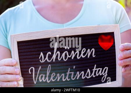 1. Februar 2024: Frau hält eine Tafel mit der Inschrift: Happy Valentinstag, FOTOMONTAGE *** Frau hält eine Tafel in der Hand mit Aufschrift: schöner Valentinstag, FOTOMONTAGE Stockfoto