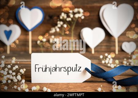 Etikett Mit Deutschem Text Fruehjahrsputz Bedeutet Frühjahrsputz. Weiße festliche und stimmungsvolle Dekoration wie Herz, Blumen und Eine blaue Schleife. Vintage, Wo Stockfoto