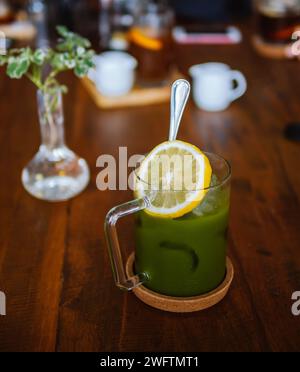 Grüner Tee Matcha Eistee und Krug und ein Zitronenpool. Eiskalte Matcha-Grüntee-Limonade in einem mauerglas auf dem hellen Hintergrund des Hauses Stockfoto