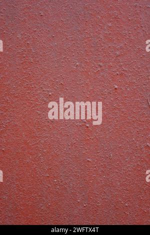 Eine alte, unebene Metalloberfläche mit Unebenheiten, die mit brauner, roter Kirschfarbe bedeckt sind. Rauer brauner, metallischer Hintergrund. Stockfoto