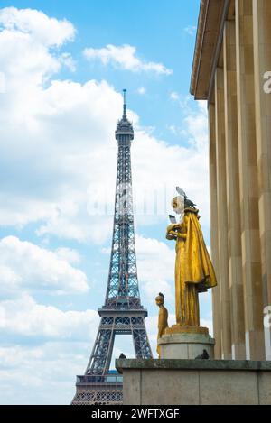 Eiffelturm und goldene Statue Les Oiseaux (eine Frau, die Tauben füttert) von Louis Brasseur, Straßentauben (Columba Livia) oder Stadttauben, auf einem sonnigen Stockfoto