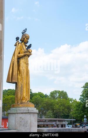 Goldene Statue Les Oiseaux (eine Taubenfütterung) von Louis Brasseur, Straßentauben (Columba Livia) oder Stadttauben, an einem sonnigen Tag mit blauem Himmel Stockfoto