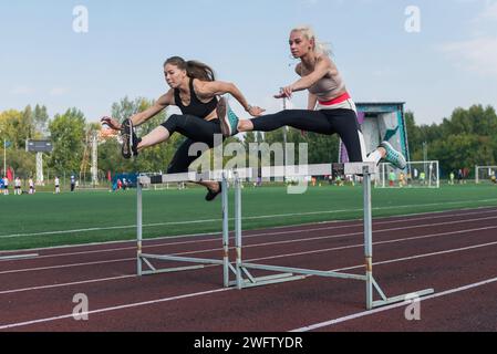 Zwei Laufsportlerinnen laufen im Stadion im Freien Hürden Stockfoto