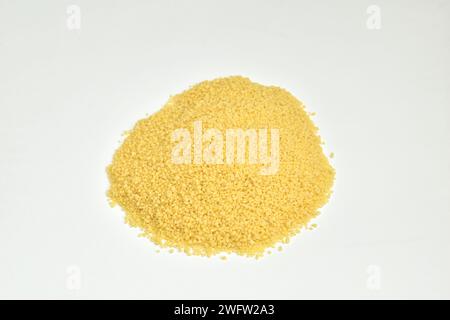 Gelbes Couscous-Getreide liegt auf einem Haufen auf weißem Hintergrund. Stockfoto