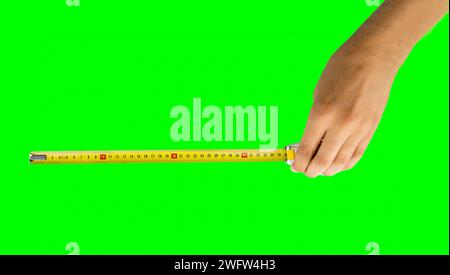 Hand mit Bandmaß, Messungen an isoliertem Ausschnitt auf grünem Hintergrund mit Chroma Key Stockfoto