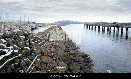 Ein langer Felsbrecher mit einem Yachthafen auf der einen Seite und dem Meer und einem Spaziersteg auf der anderen Seite. Stockfoto