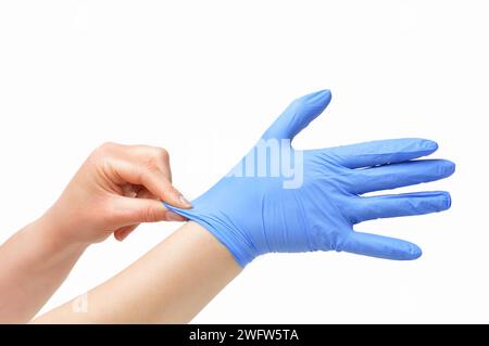 Beschnittene Aufnahme einer nicht erkennbaren Frauenhand, die Latexhandschuhe auf weißem Hintergrund anzieht Stockfoto