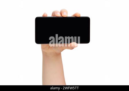 Zugeschnittene Aufnahme einer nicht erkennbaren Frauenhand, die einen schwarzen Handybildschirm auf weißem Hintergrund zeigt Stockfoto