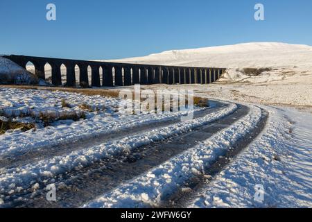 Das Ribblehead Viaduct an einem winterlichen Tag in den Yorkshire Dales in England, mit Whernside bedeckt mit Schnee im Hintergrund. An einem sonnigen Tag aufgenommen. Stockfoto