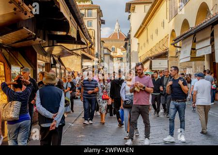 Menschenmassen laufen auf der Brücke Ponte Vecchio durch die vielen Juweliergeschäfte, die beide Seiten der Brücke in Florenz säumen Stockfoto