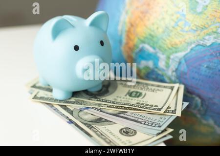 Globale Einkaufsideen. Globus mit Schweinebank, Supermarktwagen, Taschenrechner auf blauem hölzernem Hintergrund. Konzept wird gespeichert. Draufsicht Stockfoto