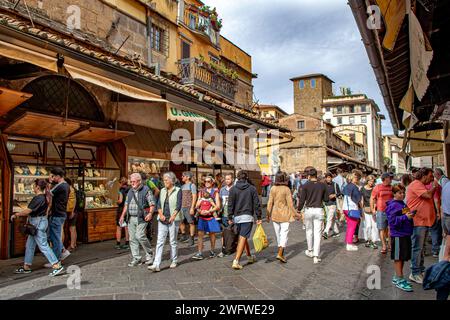 Menschenmassen laufen auf der Brücke Ponte Vecchio durch die vielen Juweliergeschäfte, die beide Seiten der Brücke in Florenz säumen Stockfoto