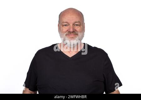 Lächelnder Bärtiger Mann mittleren Alters in schwarzem T-Shirt - selbstbewusstes Casual Porträt auf weißem Hintergrund. Stockfoto