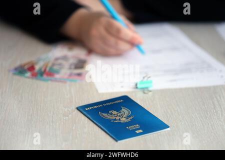 Indonesischer Pass- und Dienstleistungsarbeiter – Tabelle über den Prozess der Registrierung der Staatsbürgerschaft. Weibliche Arbeitnehmerin füllt Papiere über die Staatsbürgerschaft aus Stockfoto