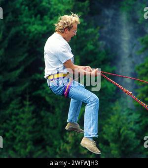 Ein junger Mann springt von einer Brücke, gesichert durch ein Seil Stockfoto