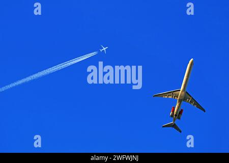 Ein tief fliegendes und ein hoch fliegendes Passagierflugzeug am blauen Himmel Stockfoto