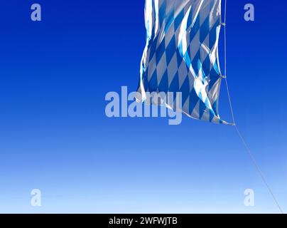 Die blauen und weißen Diamanten der bayerischen Flagge winken im Wind am blauen Himmel Stockfoto