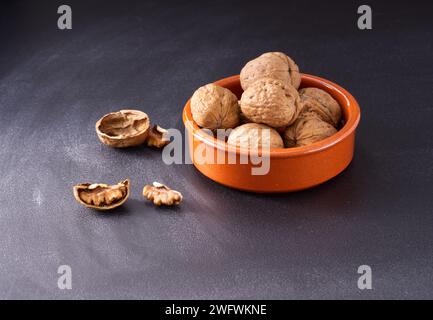 Walnüsse in keramischen Utensilien auf dunklem Hintergrund. Stockfoto