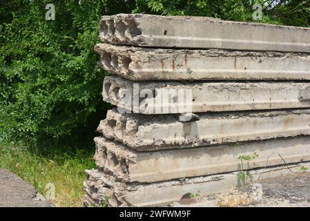 Alte graue Baumaterialien, viel Metallzement, Betonbausteine vor Ort mit Bäumen in der Natur. Stockfoto