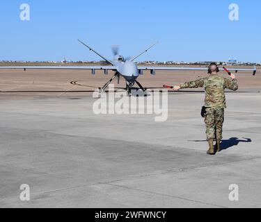 Ein Mitglied der 147th Attack Wing Aircraft Maintenance Squadron marshallt am 10. Januar 2024 einen MQ-9 Reaper zum Parken am Scholes International Airport in Galveston, Texas. Der Wing testete die Start- und Bergungsoperationen am internationalen Flughafen Scholes in Galveston als Teil seines innovativen Ansatzes für das Konzept der Agile Combat Employment. Stockfoto