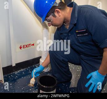 YOKOSUKA, Japan (10. Januar 2024) Aviation Boatswain’s Mate (Launch/Recovery Equipment) Airman Christian Lazaro, aus Chicago, trägt eine Schicht aus klarem Epoxid auf, während er Polyharzverbindungen auf dem Deck auf dem einzigen vorwärtsgerichteten Flugzeugträger der US Navy, USS Ronald Reagan (CVN 76) aufträgt, während im Hafen Commander, Fleet Activities Yokosuka, 10. Januar. Ronald Reagan, das Flaggschiff der Carrier Strike Group 5, stellt eine kampfbereite Truppe zur Verfügung, die die Vereinigten Staaten schützt und verteidigt und Allianzen, Partnerschaften und kollektive maritime Interessen in der indopazifischen Region unterstützt. Stockfoto