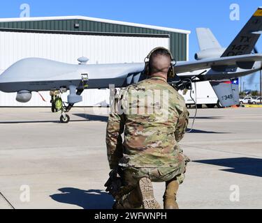 Ein Mitglied der 147th Attack Wing Aircraft Maintenance Squadron beobachtet, wie ein MQ-9 Reaper am 10. Januar 2024 am Scholes International Airport in Galveston, Texas, ein Taxi nimmt. Der Wing testete die Start- und Bergungsoperationen am internationalen Flughafen Scholes in Galveston als Teil seines innovativen Ansatzes für das Konzept der Agile Combat Employment. Stockfoto