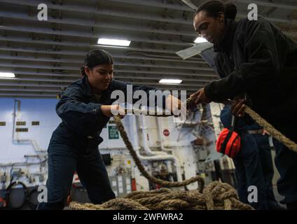 PHILIPPINE SEA (20. Januar 2024) Seaman Brenda Yilmalbe, links, von Ulithi, Mikronesien und Boatswain’s Mate 2nd Class Alexius Cyprian, rechts, von Covington, Louisiana, beide dem vorwärtsgerichteten amphibischen Angriffsträger USS America (LHA 6) zugeteilt, Spulen Sie eine Linie in der Hangarbucht des Schiffes während eines Auffüllens auf See mit dem Flottenauffüllöler USNS John Ericsson (T-AO-194), während Sie am 20. Juli in der Philippinischen See segeln. America, Leitschiff der America Amphibious Ready Group, ist im Einsatzgebiet der 7. US-Flotte im Einsatz. Die 7. US-Flotte ist der größte Vorwärtsdeplo der US Navy Stockfoto