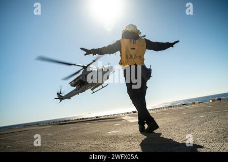 Die US Navy Aviation Boatswain’s Mate (Handling) 3rd Class Jamaal Phillips, die dem amphibischen Angriffsschiff USS Boxer (LHD 4) zugeteilt wurde, und ein Eingeborener aus Atlanta leitet ein Marine Corps AH-1Z Viper, das der Marine Medium Tiltrotor Squadron (VMM) 165 (verstärkt), 15. Marine Expeditionstruppe angehört, während er am 4. Januar 2024 an Bord von Boxer im Pazifischen Ozean landet. Die 15. MEU ist derzeit an Bord der Boxer Amphibious Ready Group, die integrierte Trainings- und Routineoperationen in der 3. US-Flotte durchführt. Stockfoto