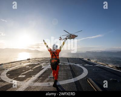 Ein Besatzungsmitglied von der Küstenwache Cutter Alex Haley, das Hubschrauberoperationen mit der Küstenwache Kodiak MH-60 Jayhawk Hubschrauberflugbesatzung in der Beringsee durchführt, 8. Januar 2024. Diese Hubschrauberoperationen beinhalteten das HIFR-Training (Helicopter in Flight Betankung). Während dieses HIFR-Trainings betankten die Cutter-Crew und die Hubschraubercrew den Hubschrauber, während er über dem Flugdeck des Cutters schweben ließ. Die HIFR-Methode wird zum Auftanken von Hubschraubern verwendet, die zu groß sind, um auf dem Cockpit untergebracht zu werden, oder wenn die Bewegung des Flugdecks außerhalb der Grenzen liegt. Ein weiterer zusätzlicher Vorteil eines HIFR m Stockfoto